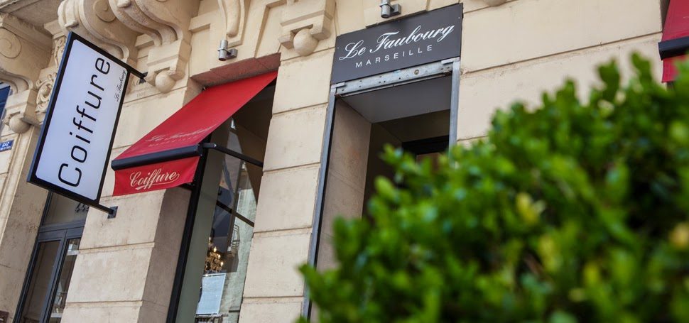 La façade du salon Le Faubourg au 442 rue Paradis à Marseille : enseigne noire et store rouge Coiffure